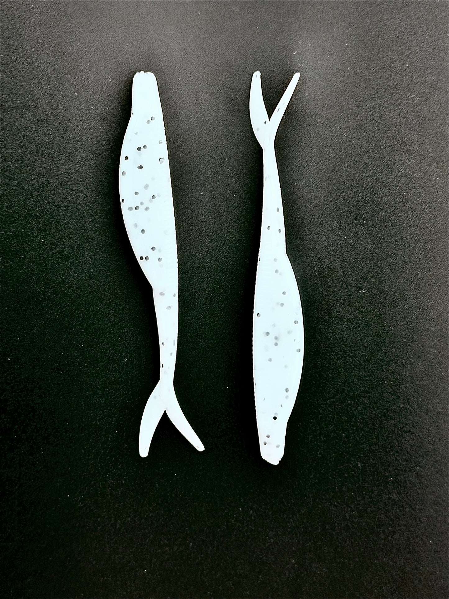 Two white fishing lures on a black background