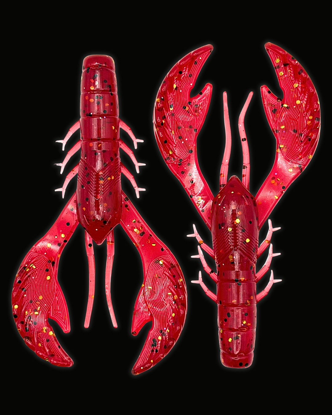 Two red crawfish-shaped soft plastic fishing lures with glittery gold, black, and white speckles, shown from front and back views against a solid black background.