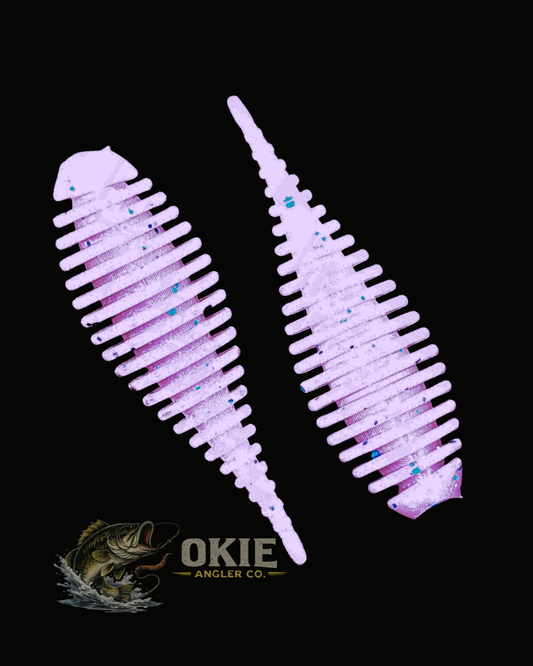 Two light purple soft plastic fishing lures with blue glitter flakes, displayed on a solid black background with the Okie Angler Co. logo at the bottom.