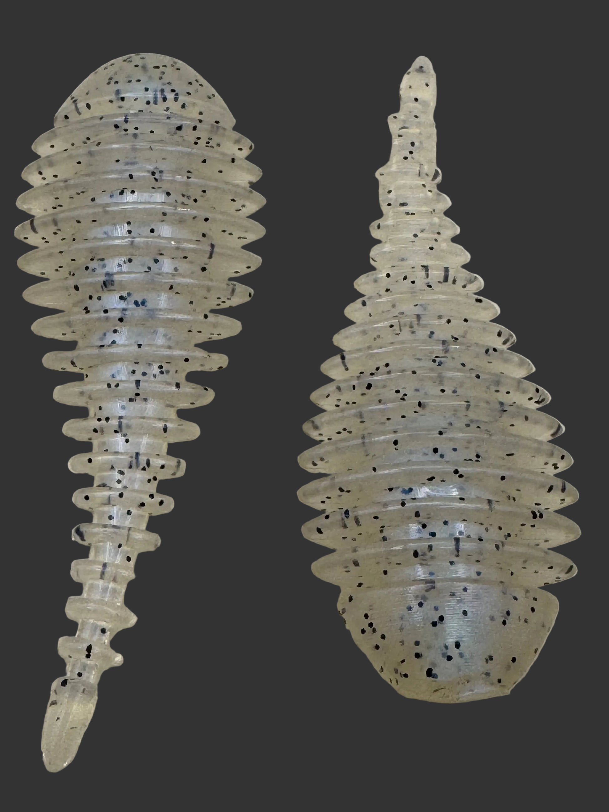 Two transparent fishing lures with black specks on a beige background
