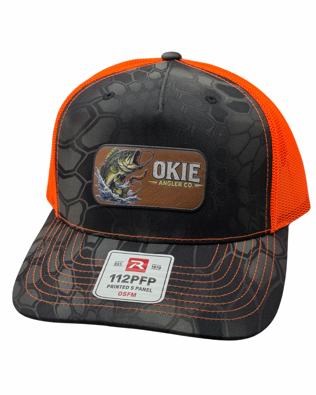 A trucker-style cap with a black and gray reptile-patterned front panel and brim, bright orange mesh back, and orange contrast stitching. A brown patch on the front reads 'OKIE Angler Co.